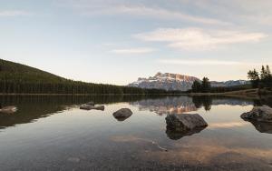 Forest reflection over a calm lake with mountain in the background
